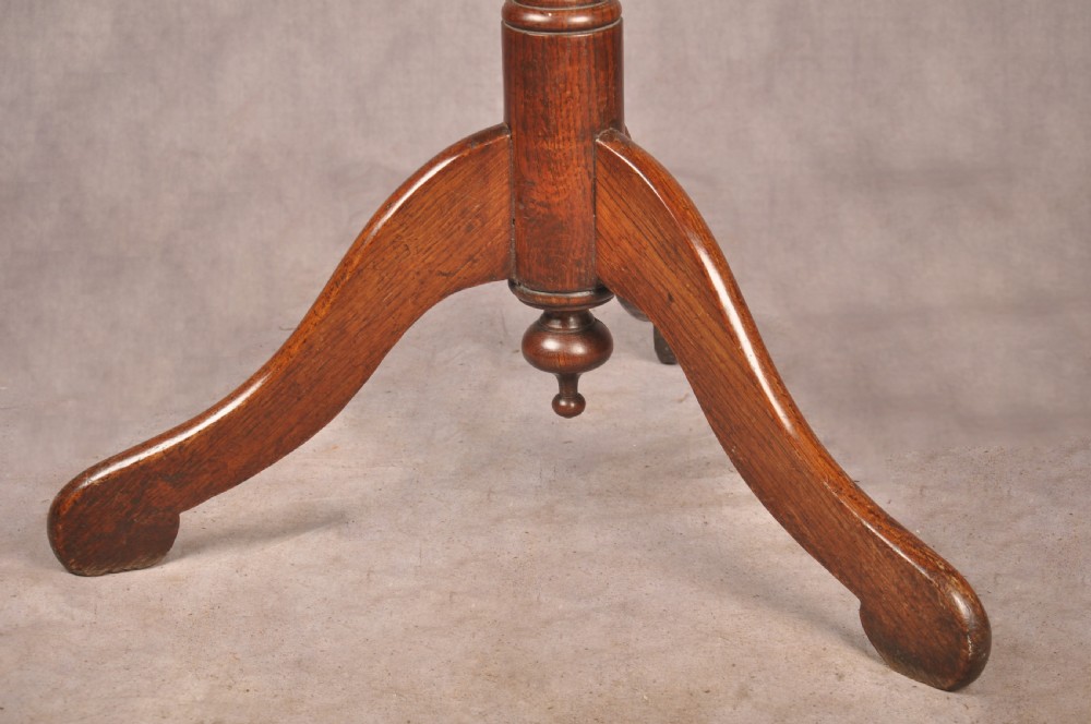 An 18th-century dark oak tripod table featuring a circular top, turned spindle birdcage stem, and three splayed cabriole legs. View V