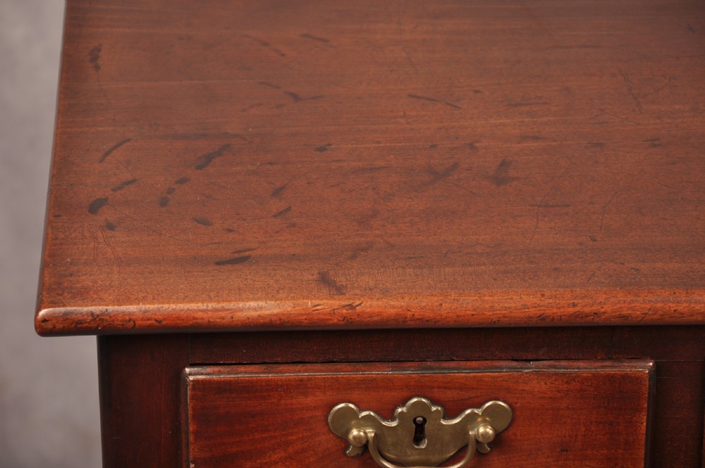 An early 18th-century mahogany lowboy with three drawers, brass handles, a shaped apron, and four cabriole legs with pad feet. View VIII