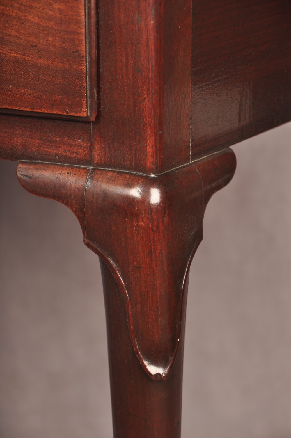 An early 18th-century mahogany lowboy with three drawers, brass handles, a shaped apron, and four cabriole legs with pad feet. View X