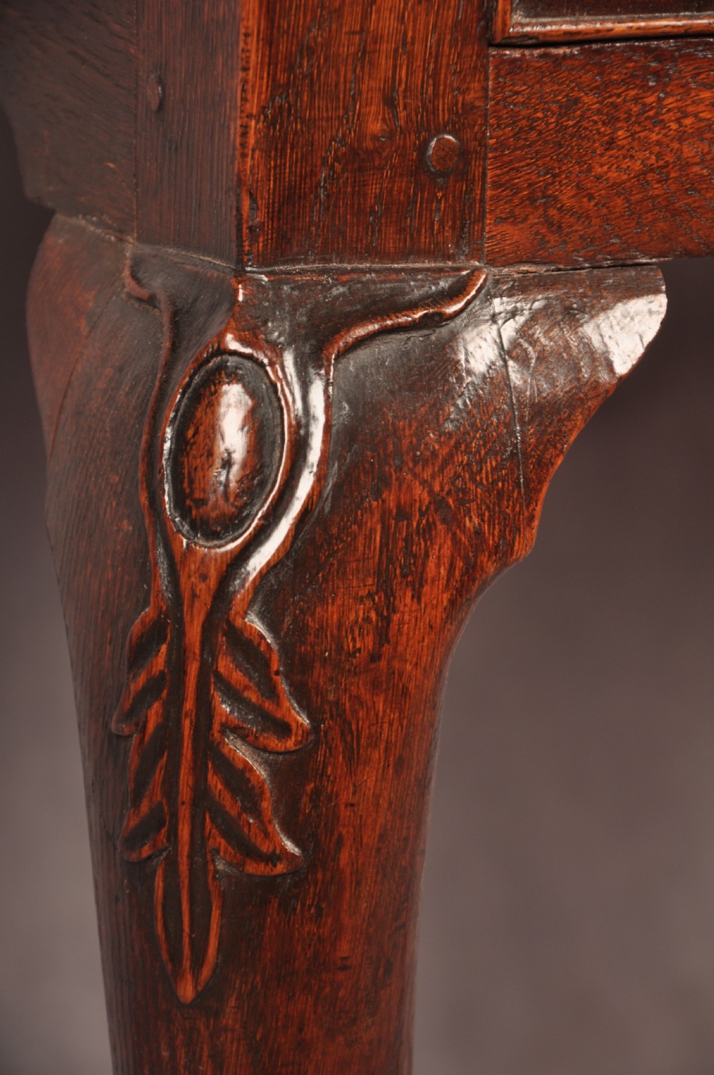 An early 18th-century dark oak lowboy side table featuring three drawers with brass drop handles, a shaped apron, and four cabriole legs. View VI