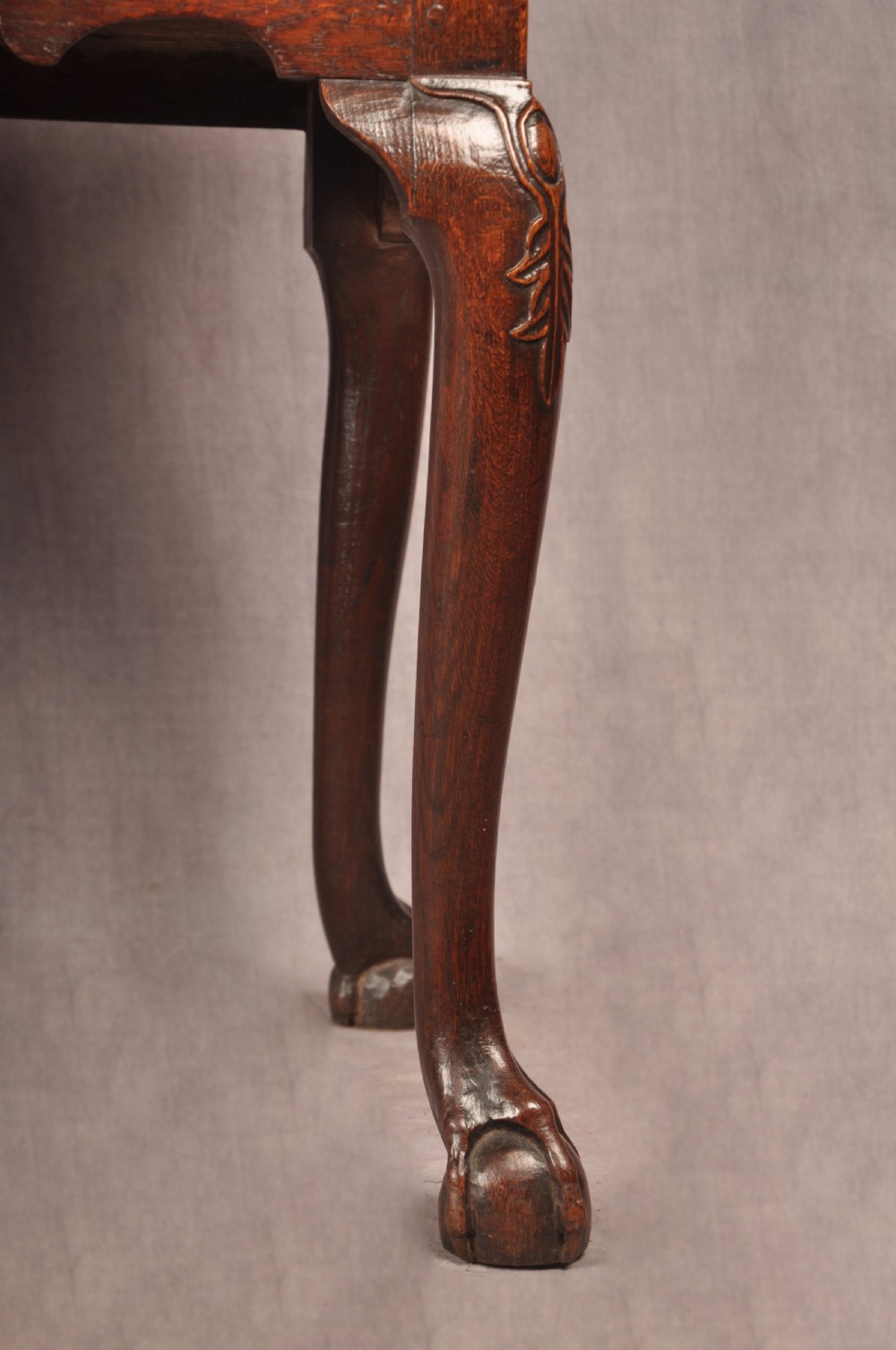 An early 18th-century dark oak lowboy side table featuring three drawers with brass drop handles, a shaped apron, and four cabriole legs. View VII