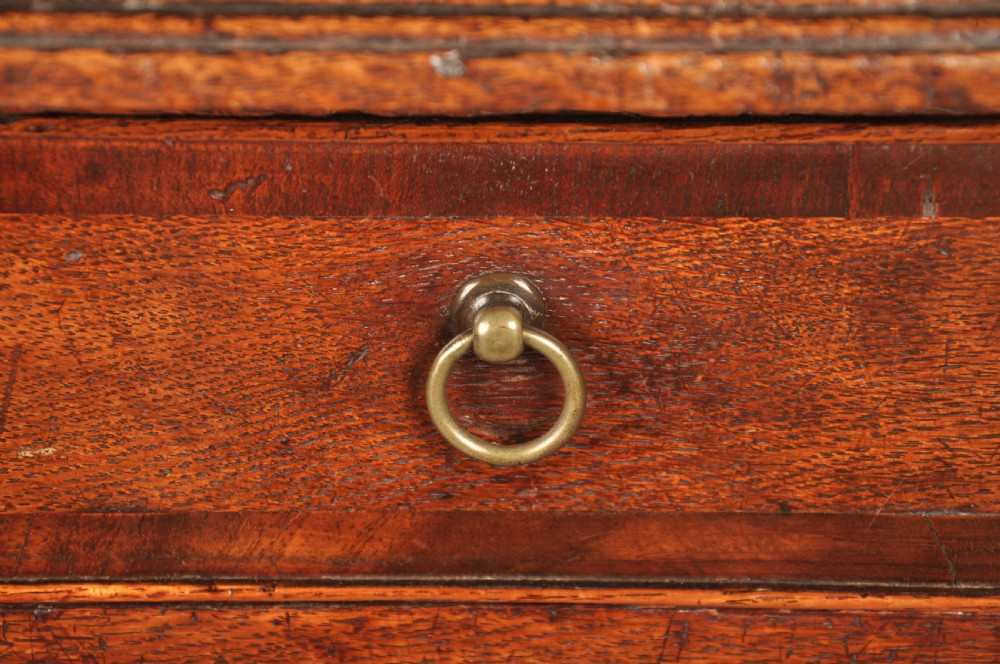 An early 18th-century dark oak lowboy side table featuring three drawers with brass drop handles, a shaped apron, and four cabriole legs. View XI