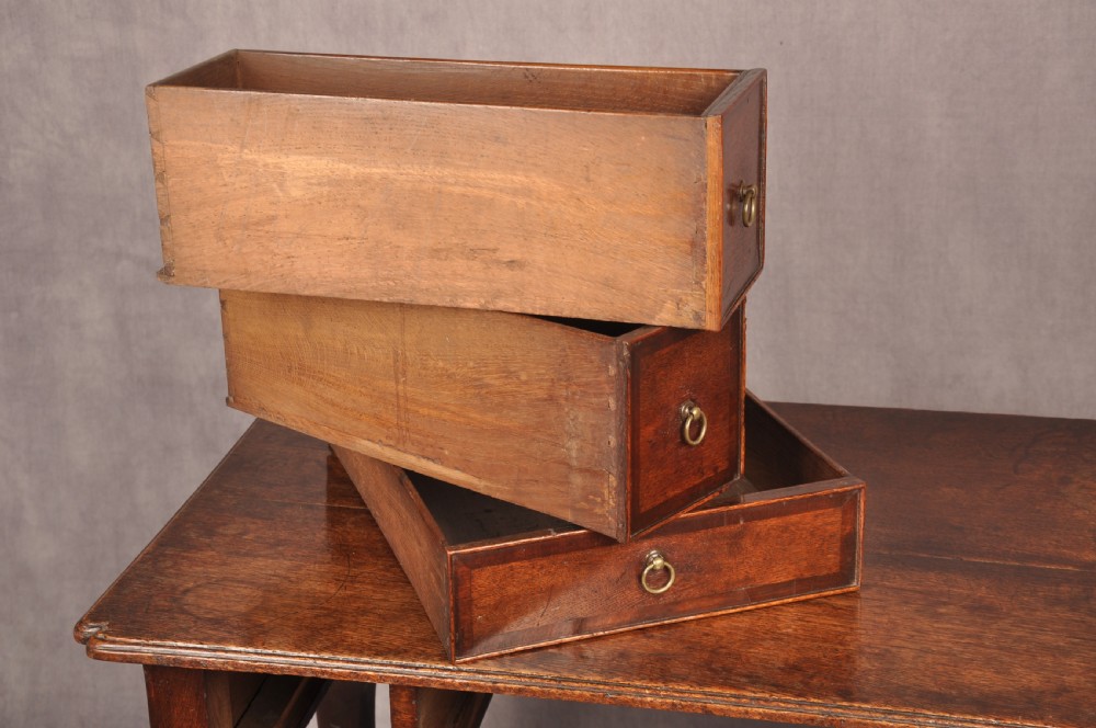 An early 18th-century dark oak lowboy side table featuring three drawers with brass drop handles, a shaped apron, and four cabriole legs. View XII
