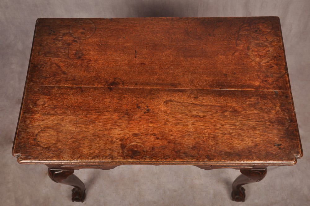 An early 18th-century dark oak lowboy side table featuring three drawers with brass drop handles, a shaped apron, and four cabriole legs. View XVI