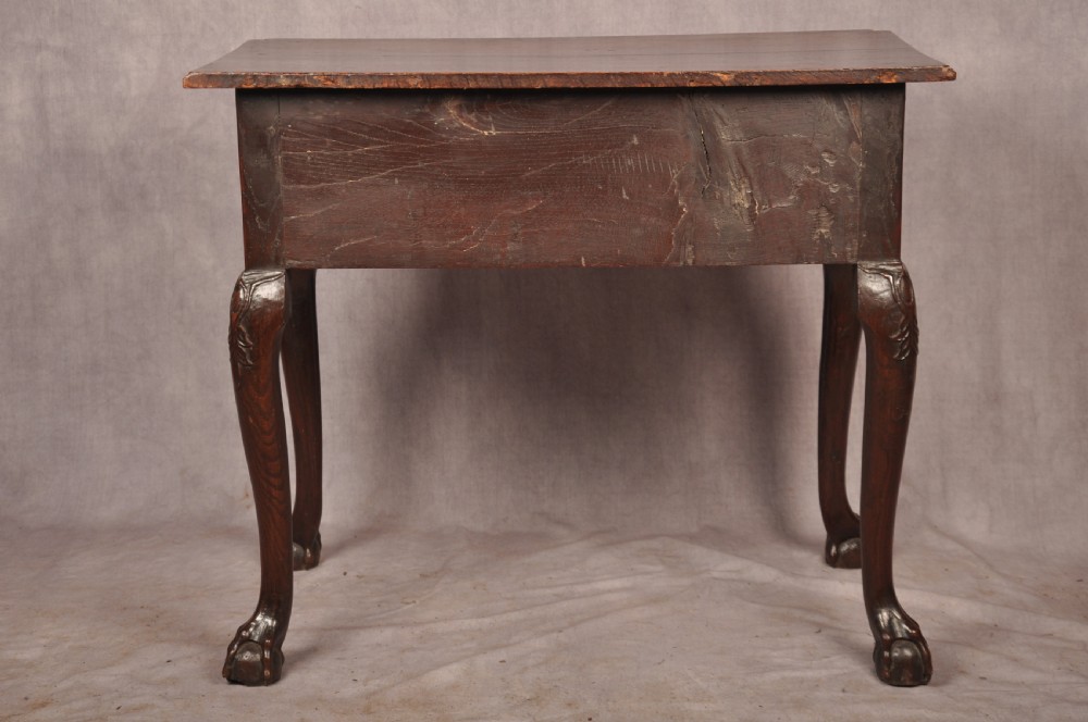 An early 18th-century dark oak lowboy side table featuring three drawers with brass drop handles, a shaped apron, and four cabriole legs. View XX
