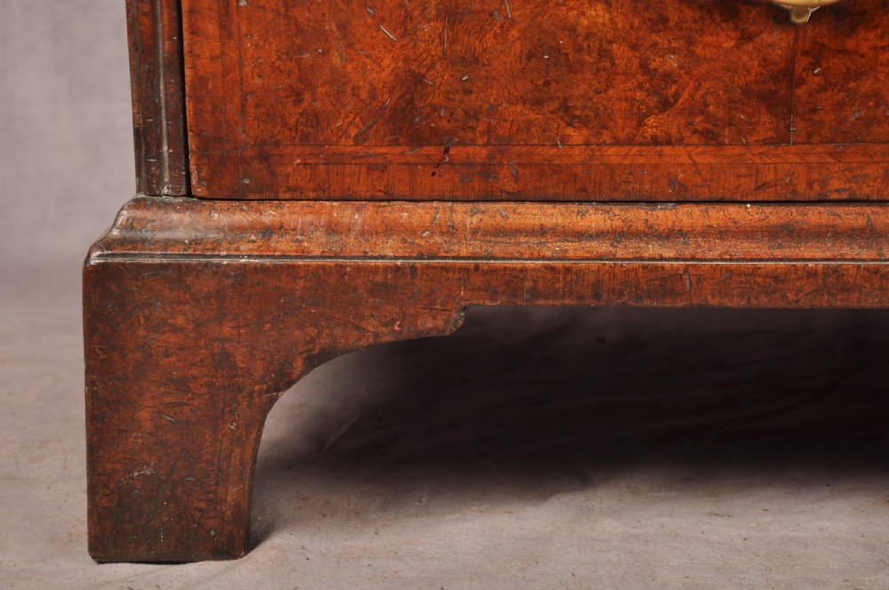 An early 18th-century burr walnut slant-front bureau featuring brass drop handles, keyhole escutcheons, and a chest of drawers base. View XI