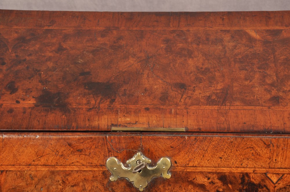 An early 18th-century burr walnut slant-front bureau featuring brass drop handles, keyhole escutcheons, and a chest of drawers base. View XIII