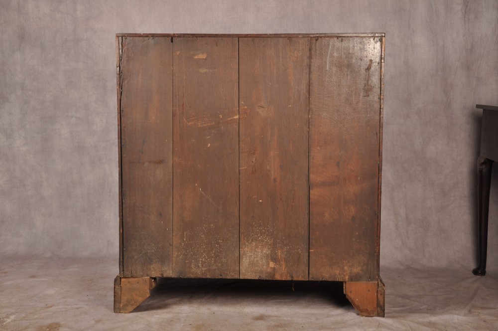 An early 18th-century burr walnut slant-front bureau featuring brass drop handles, keyhole escutcheons, and a chest of drawers base. View XVI