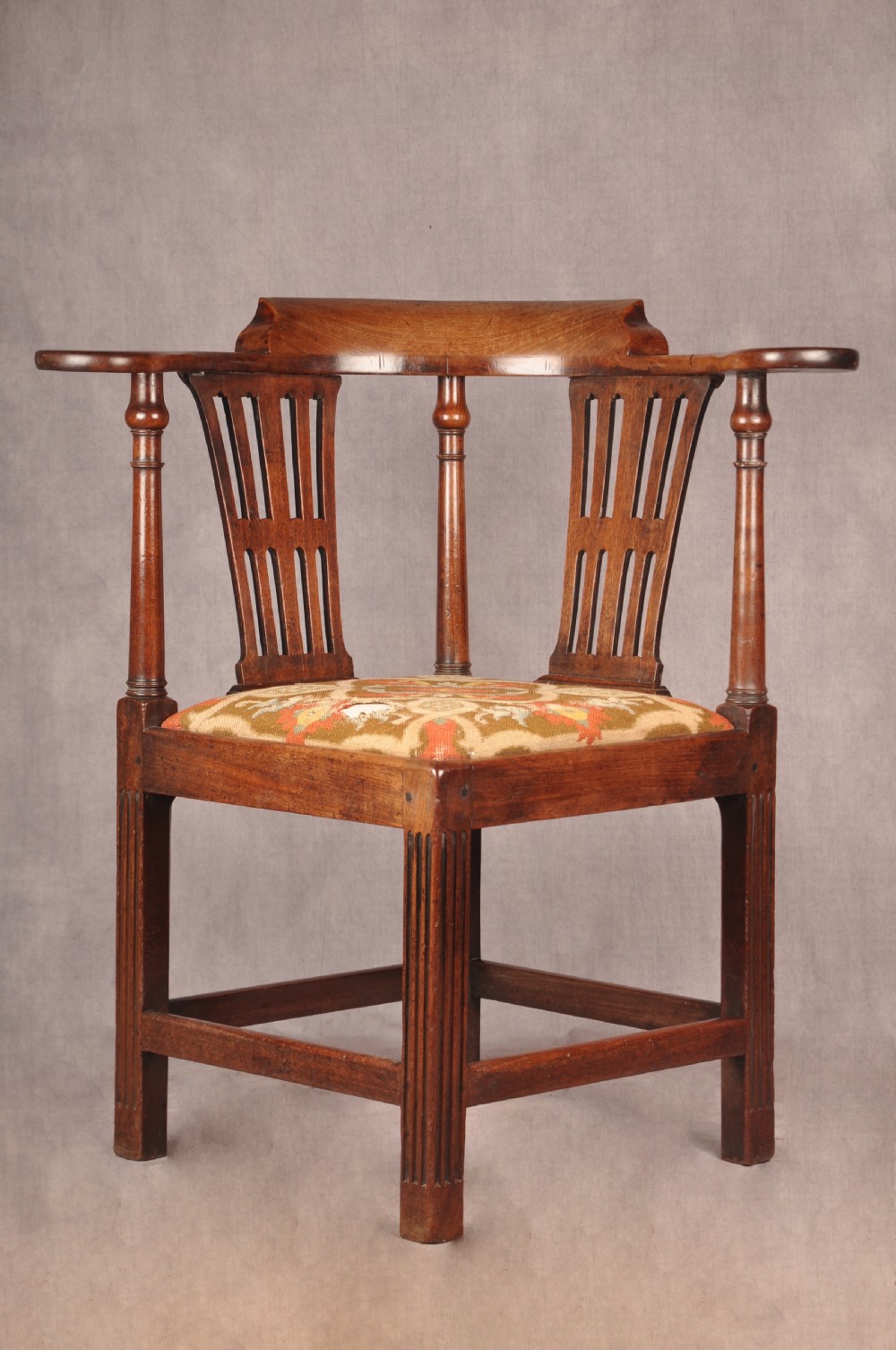 An 18th-century dark wood corner chair featuring a curved horseshoe backrest, dual pierced splats, turned uprights, fluted legs, and a patterned needlepoint drop-in seat. View II