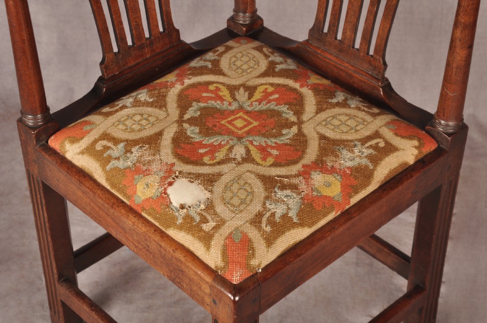 An 18th-century dark wood corner chair featuring a curved horseshoe backrest, dual pierced splats, turned uprights, fluted legs, and a patterned needlepoint drop-in seat. View III