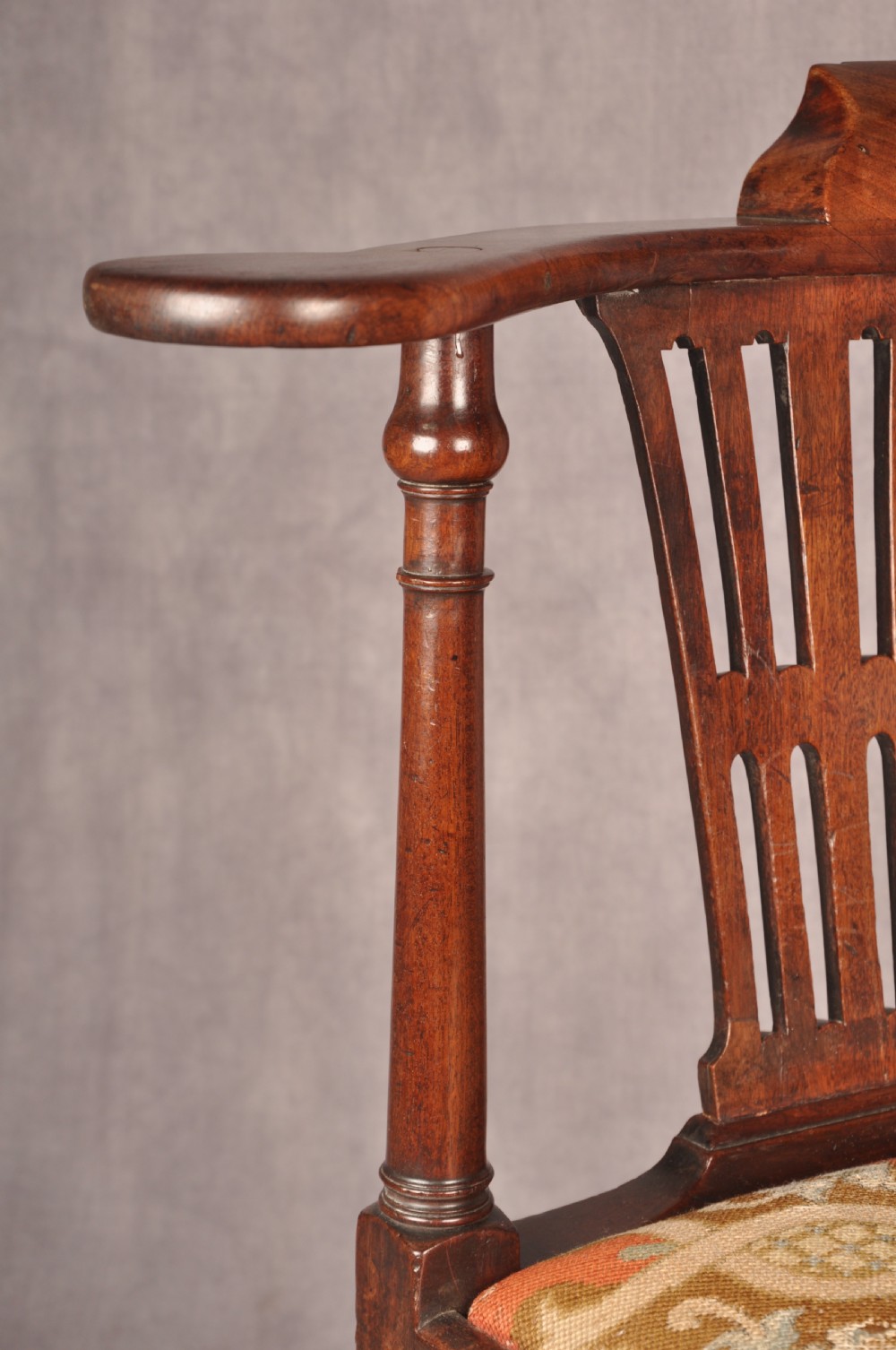 An 18th-century dark wood corner chair featuring a curved horseshoe backrest, dual pierced splats, turned uprights, fluted legs, and a patterned needlepoint drop-in seat. View VI