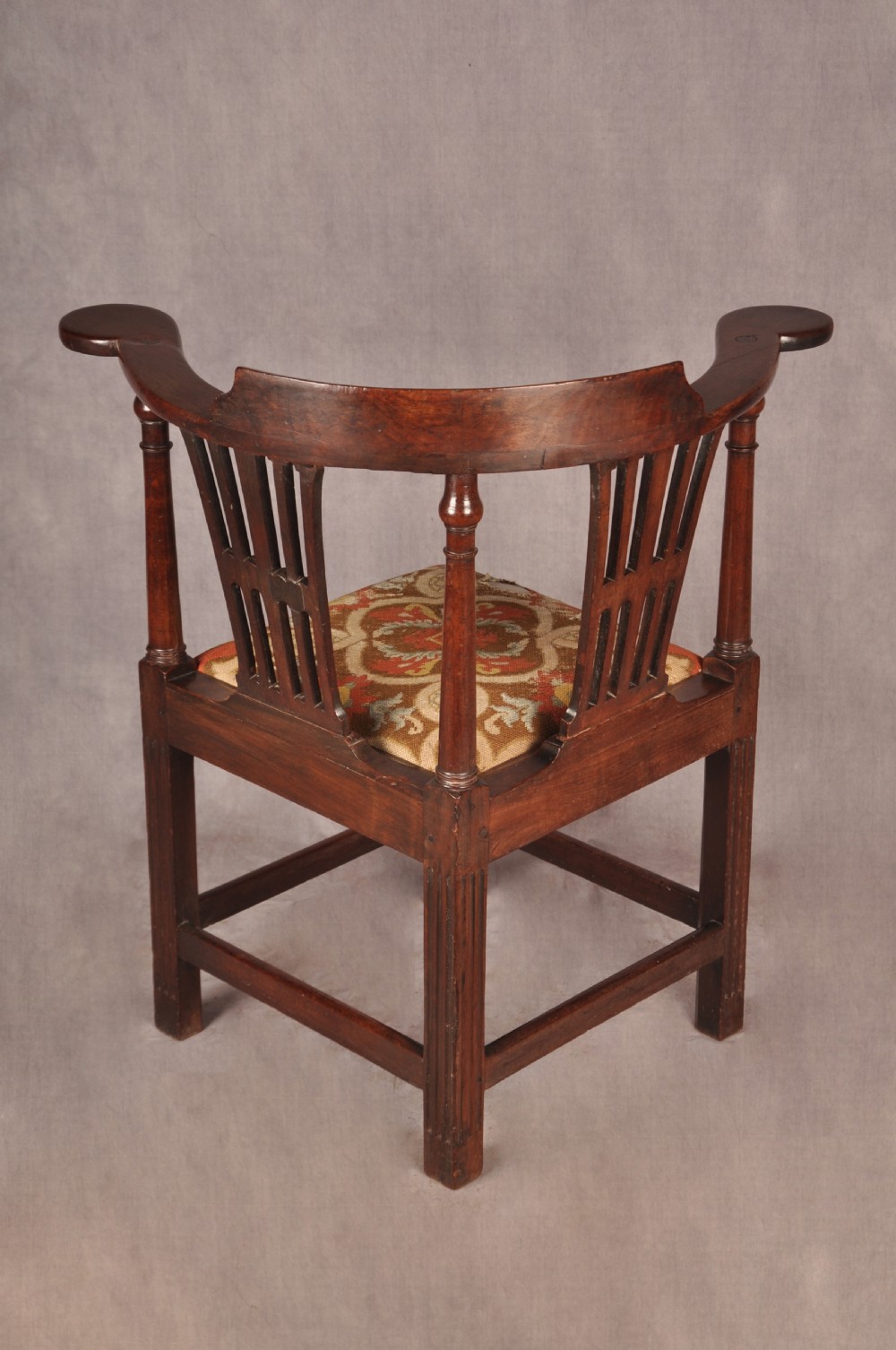 An 18th-century dark wood corner chair featuring a curved horseshoe backrest, dual pierced splats, turned uprights, fluted legs, and a patterned needlepoint drop-in seat. View XIII
