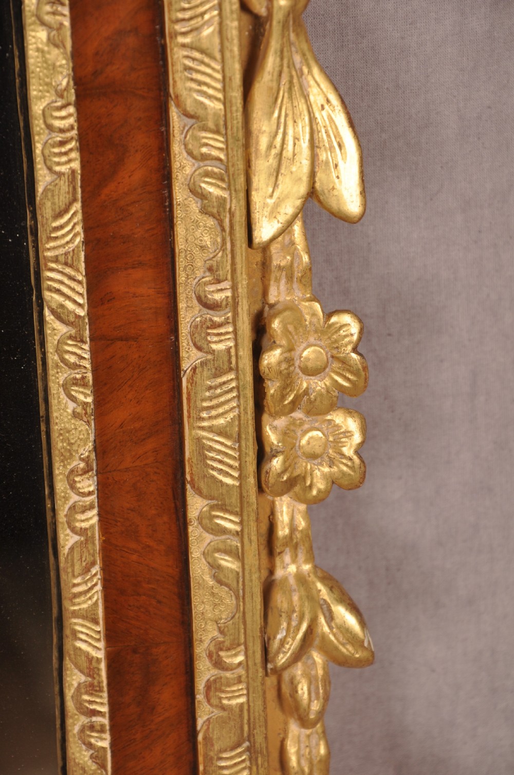 An 18th-century walnut and parcel gilt wall mirror featuring a carved swan-neck pediment, central cartouche crest, and floral side pendants. View II