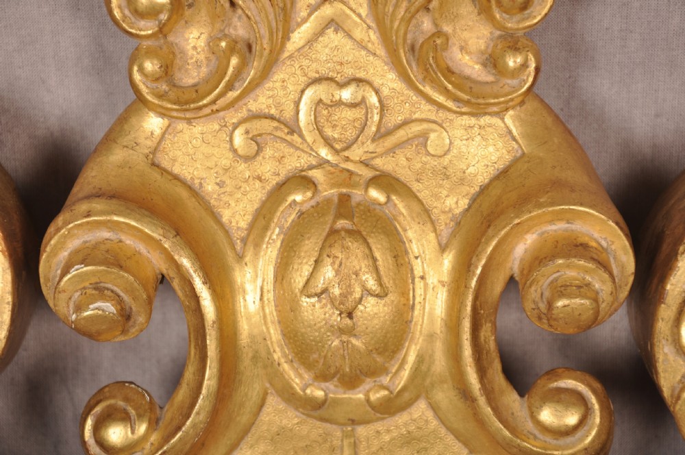 An 18th-century walnut and parcel gilt wall mirror featuring a carved swan-neck pediment, central cartouche crest, and floral side pendants. View IV