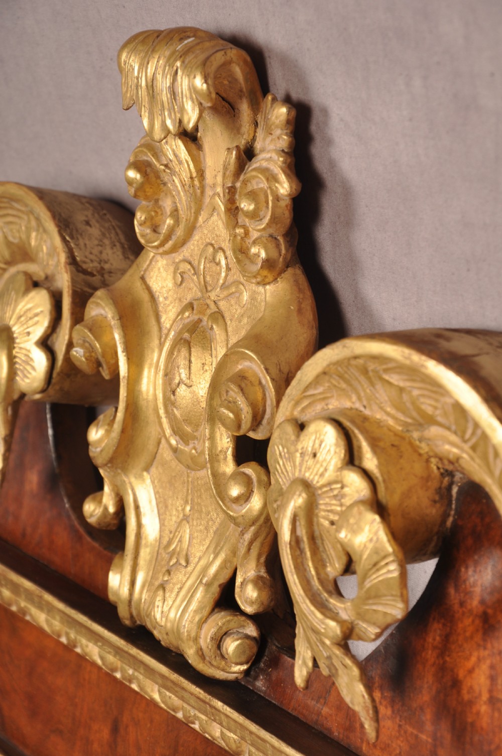 An 18th-century walnut and parcel gilt wall mirror featuring a carved swan-neck pediment, central cartouche crest, and floral side pendants. View VII