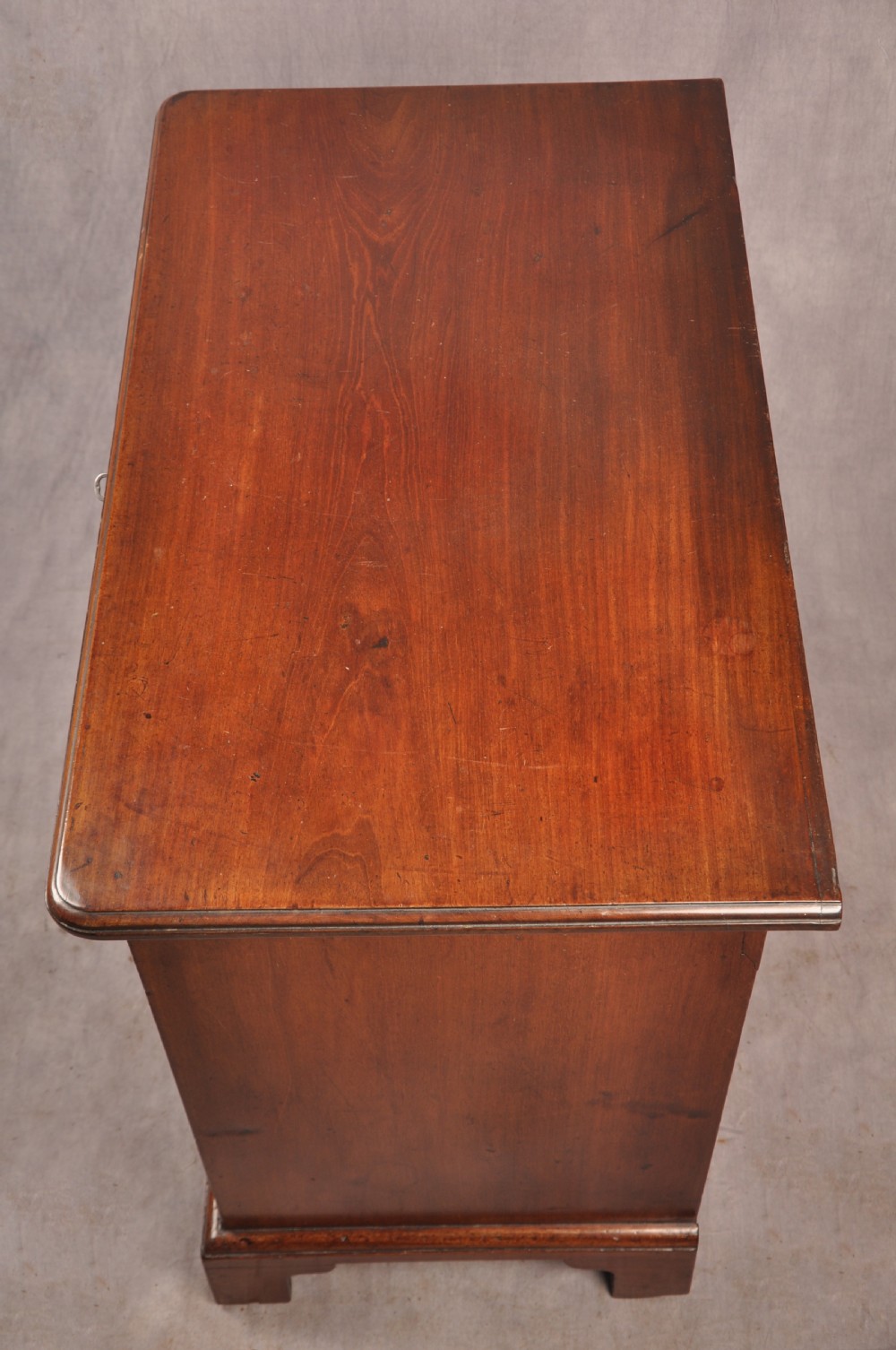 An 18th-century mahogany kneehole desk featuring multiple drawers with brass swan-neck handles, a central recessed cupboard, and bracket feet. View III