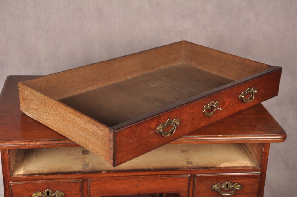 An 18th-century mahogany kneehole desk featuring multiple drawers with brass swan-neck handles, a central recessed cupboard, and bracket feet. View VII