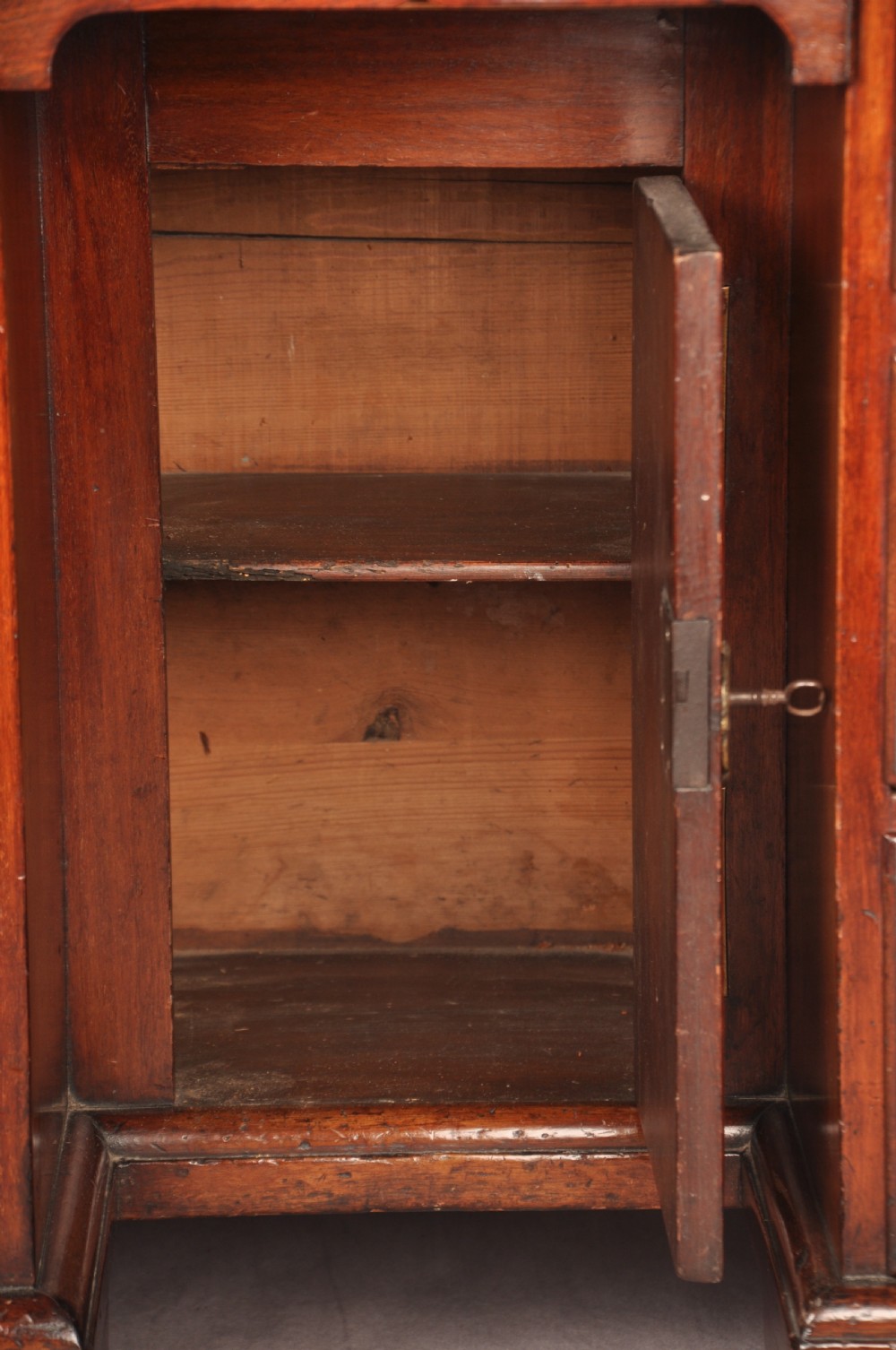 An 18th-century mahogany kneehole desk featuring multiple drawers with brass swan-neck handles, a central recessed cupboard, and bracket feet. View XII