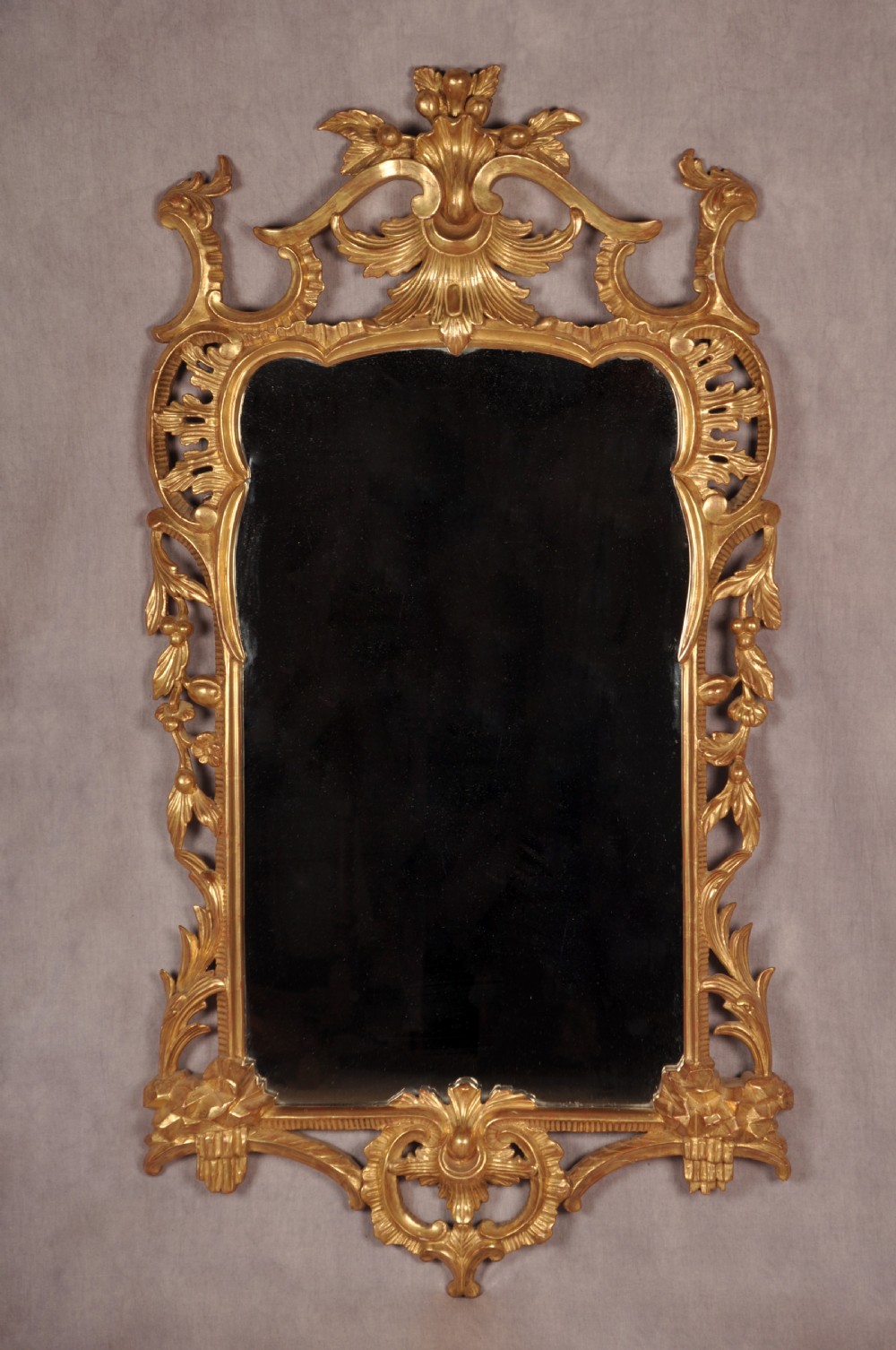 An ornate late nineteenth-century giltwood wall mirror featuring carved acanthus leaf scrollwork and an arched mirror plate.
