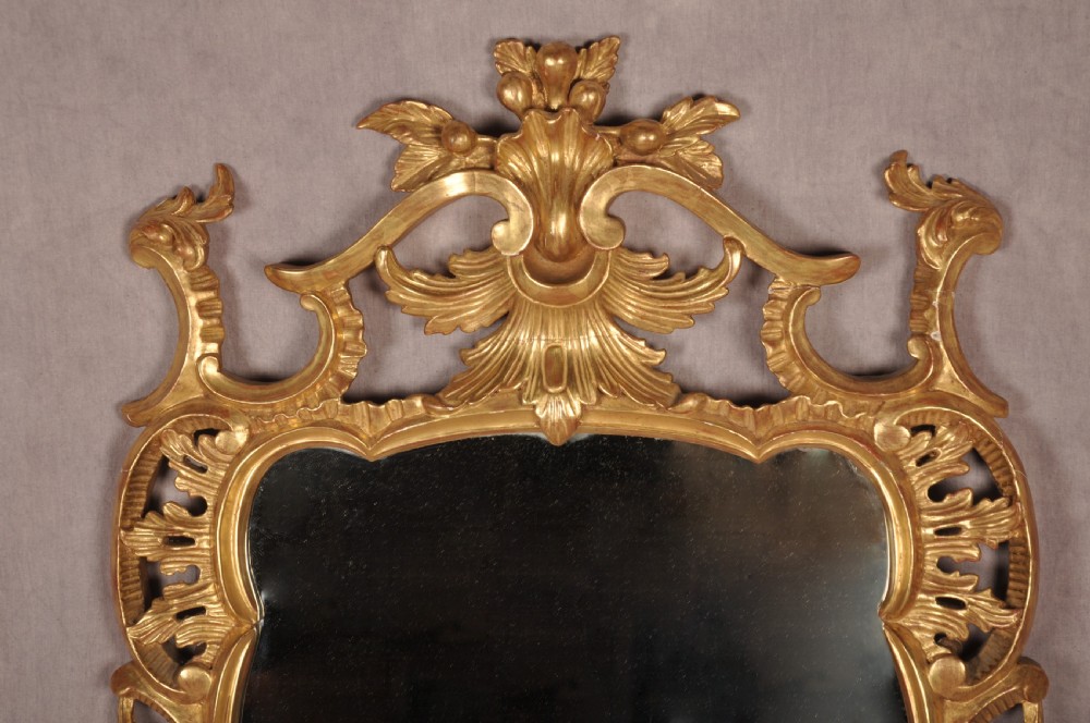 An ornate late nineteenth-century giltwood wall mirror featuring carved acanthus leaf scrollwork and an arched mirror plate. View II