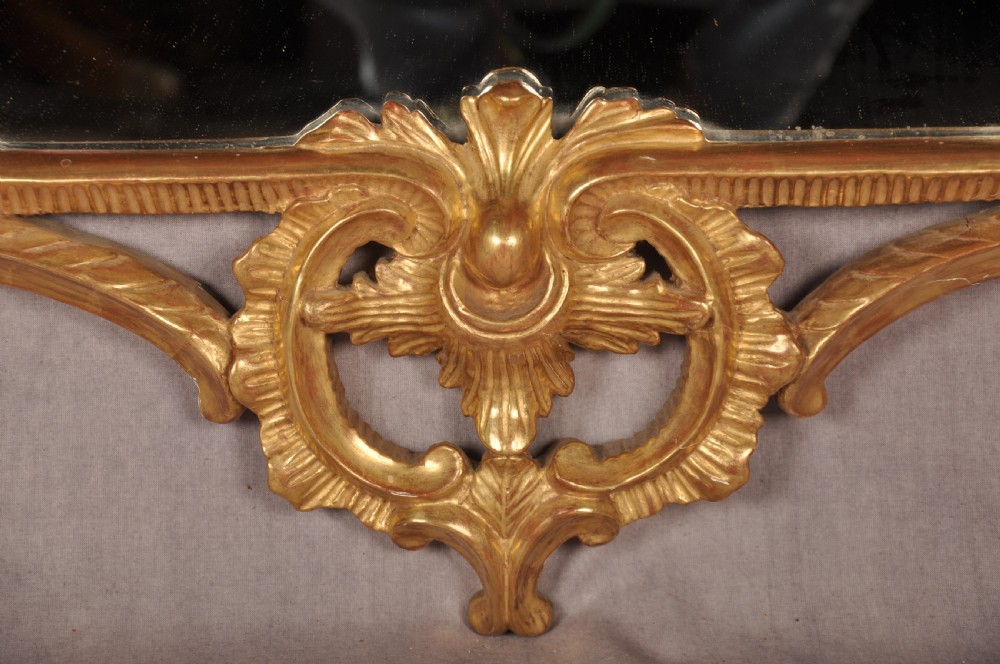 An ornate late nineteenth-century giltwood wall mirror featuring carved acanthus leaf scrollwork and an arched mirror plate. View V