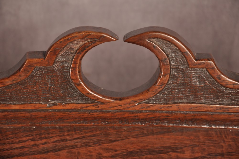 A pair of 17th century dark oak side chairs featuring carved crest rails, solid panel backs, and bobbin-turned front stretchers. View III