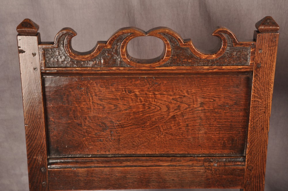 A pair of 17th century dark oak side chairs featuring carved crest rails, solid panel backs, and bobbin-turned front stretchers. View IV
