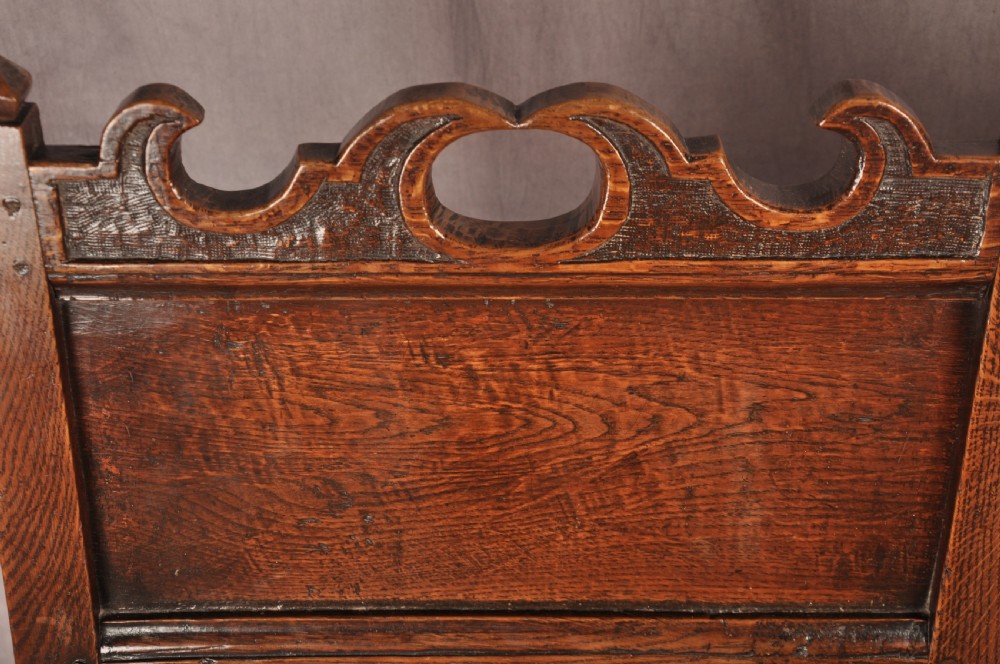 A pair of 17th century dark oak side chairs featuring carved crest rails, solid panel backs, and bobbin-turned front stretchers. View VI