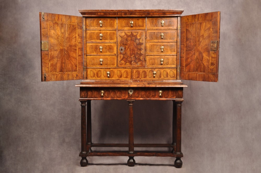 A 17th-century olive wood cabinet on stand featuring double doors inlaid with oval oyster veneer medallions, a lower drawer, turned legs, stretchers, and ball feet. View II