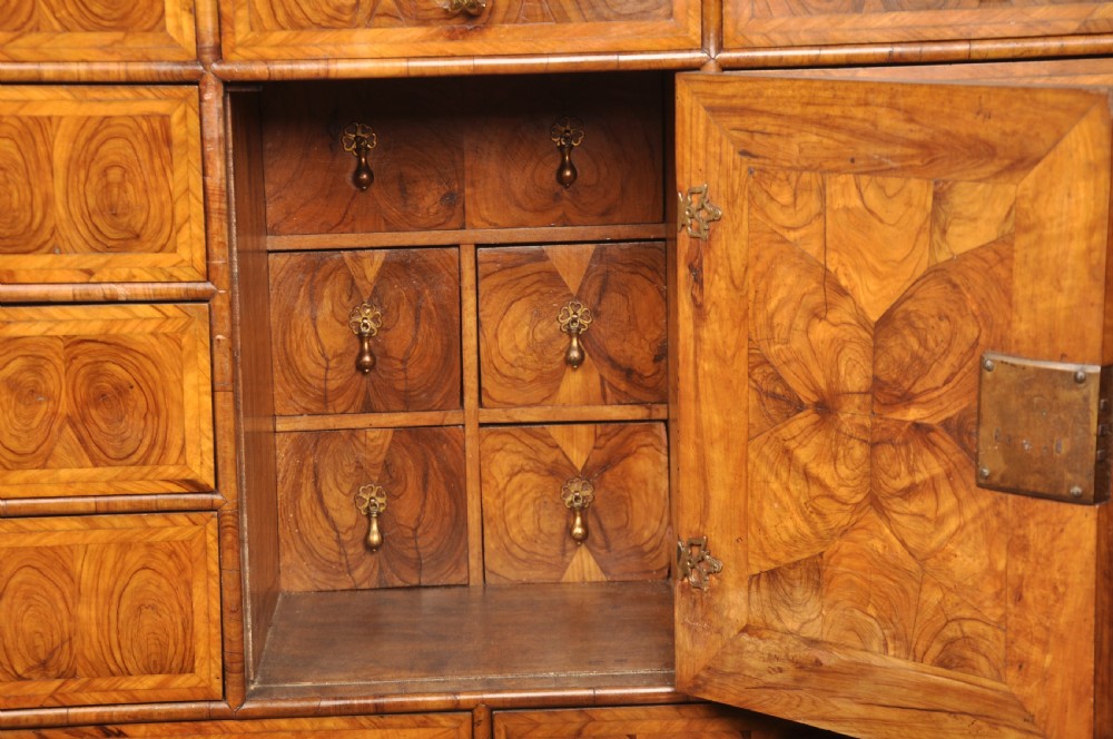 A 17th-century olive wood cabinet on stand featuring double doors inlaid with oval oyster veneer medallions, a lower drawer, turned legs, stretchers, and ball feet. View IV