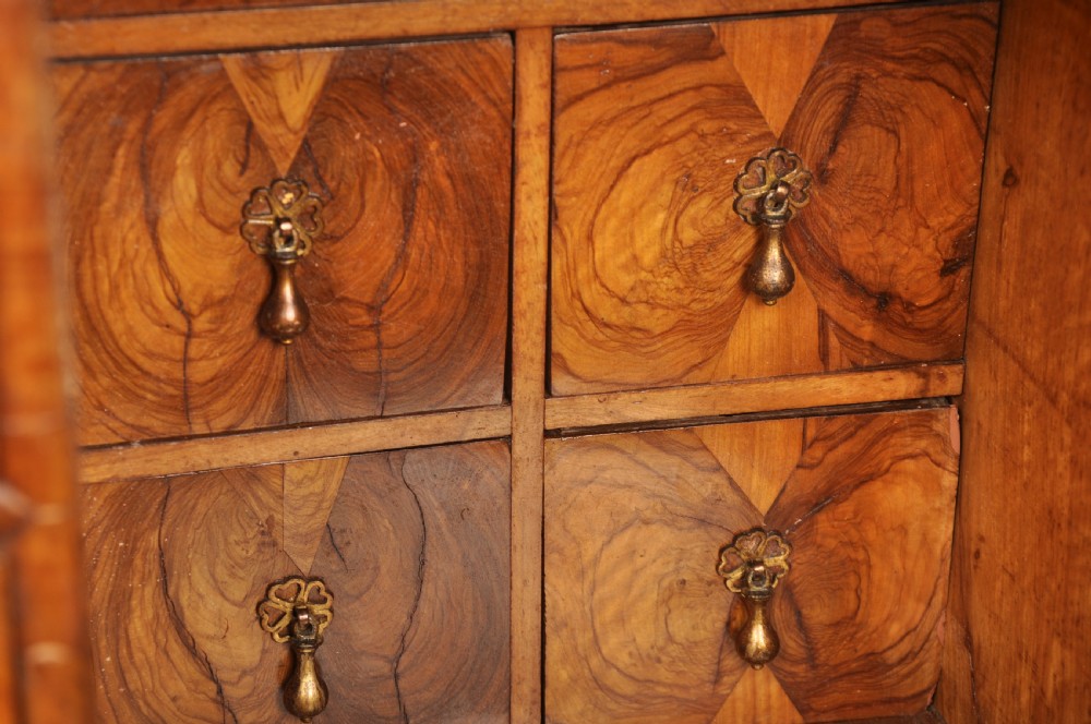 A 17th-century olive wood cabinet on stand featuring double doors inlaid with oval oyster veneer medallions, a lower drawer, turned legs, stretchers, and ball feet. View V