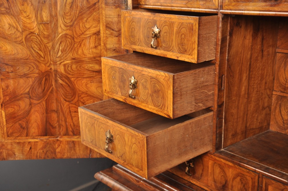 A 17th-century olive wood cabinet on stand featuring double doors inlaid with oval oyster veneer medallions, a lower drawer, turned legs, stretchers, and ball feet. View IX