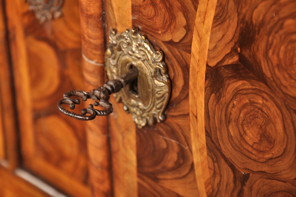 A 17th-century olive wood cabinet on stand featuring double doors inlaid with oval oyster veneer medallions, a lower drawer, turned legs, stretchers, and ball feet. View XIV