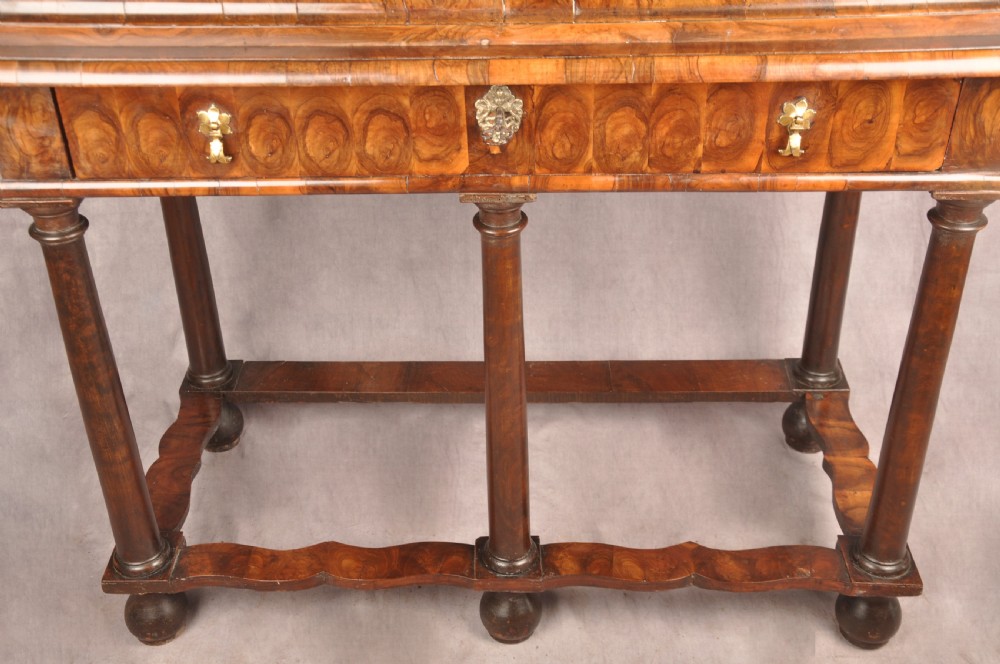 A 17th-century olive wood cabinet on stand featuring double doors inlaid with oval oyster veneer medallions, a lower drawer, turned legs, stretchers, and ball feet. View XX