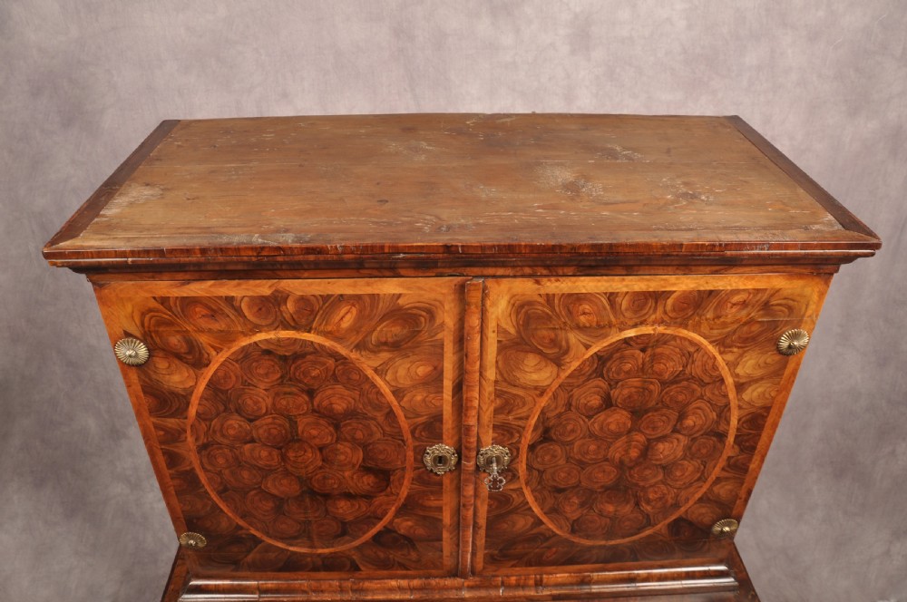 A 17th-century olive wood cabinet on stand featuring double doors inlaid with oval oyster veneer medallions, a lower drawer, turned legs, stretchers, and ball feet. View XXIII