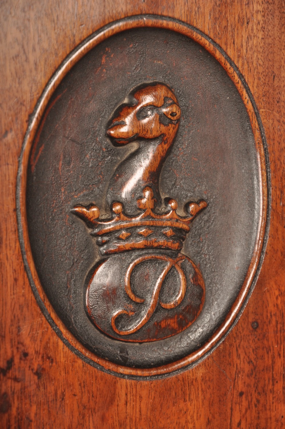A pair of antique dark mahogany Regency hall chairs featuring solid seats, turned front legs, and shaped backrests decorated with oval armorial crest medallions. View VI