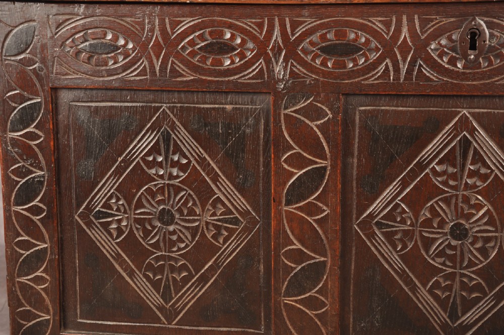 A 17th century carved oak coffer featuring three lozenge-carved front panels, leaf motifs, and ebonised detailing. View IV