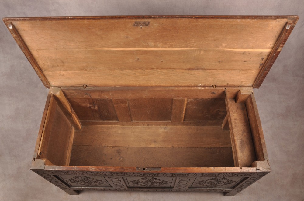 A 17th century carved oak coffer featuring three lozenge-carved front panels, leaf motifs, and ebonised detailing. View V