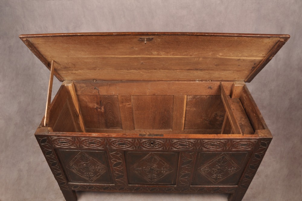 A 17th century carved oak coffer featuring three lozenge-carved front panels, leaf motifs, and ebonised detailing. View VI