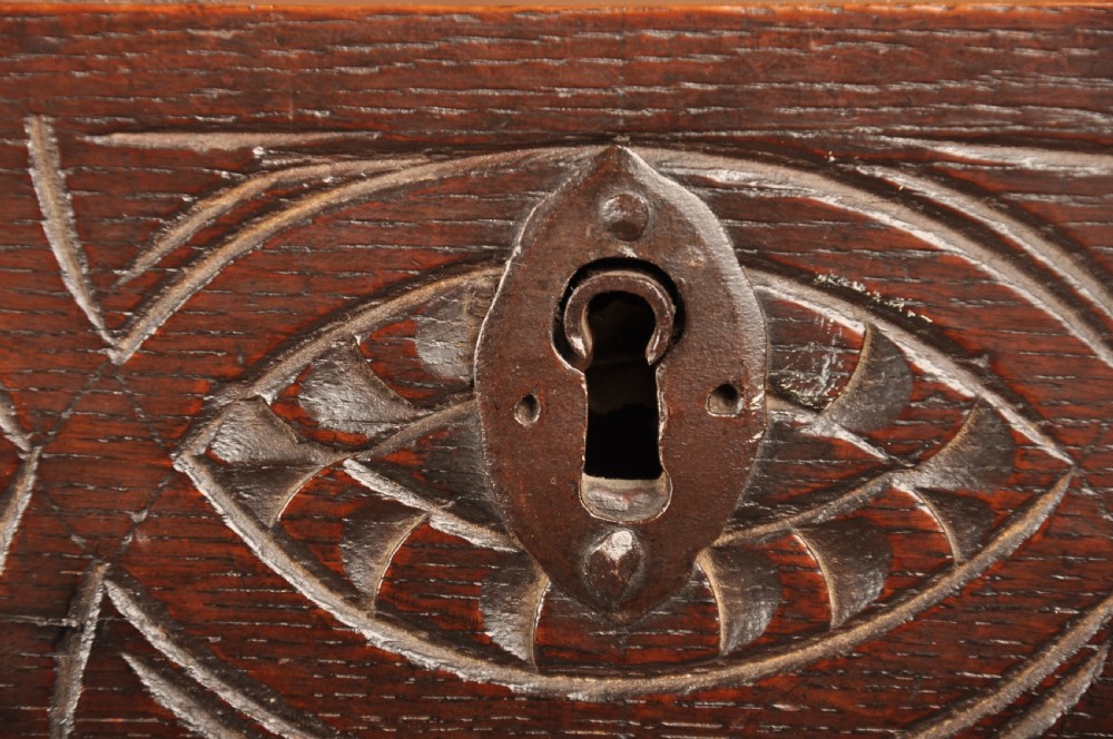 A 17th century carved oak coffer featuring three lozenge-carved front panels, leaf motifs, and ebonised detailing. View X