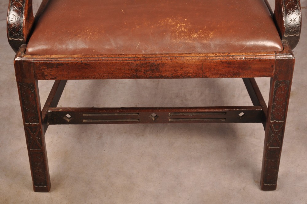 An 18th-century Chippendale carved mahogany armchair with a pierced splat, carved stretcher base, curved arms, and a warm brown leather seat. View V
