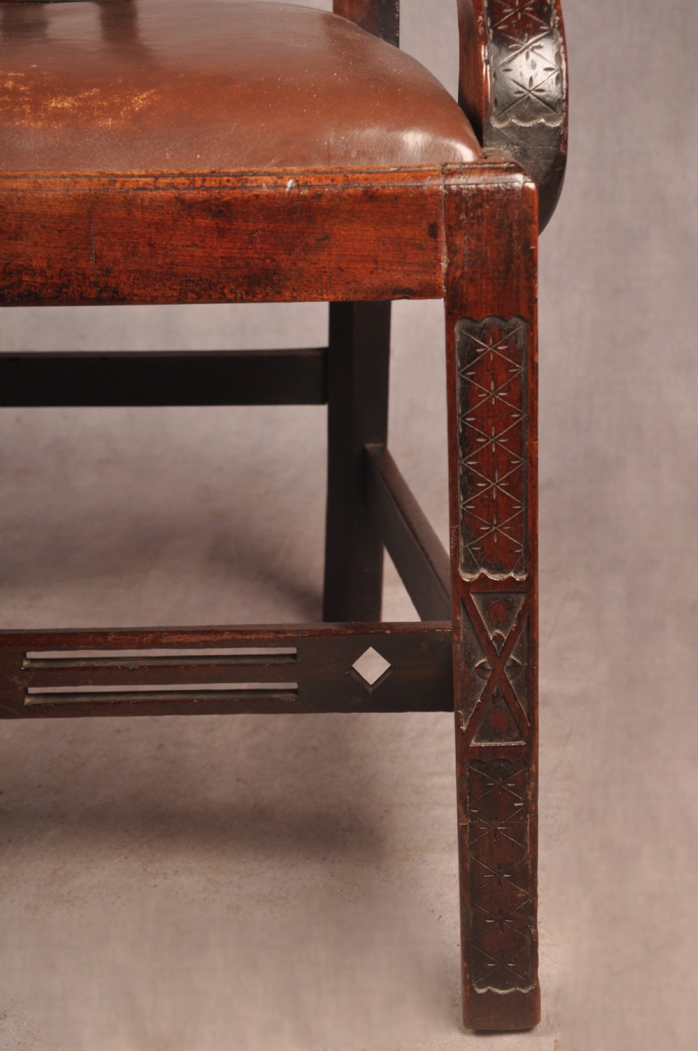 An 18th-century Chippendale carved mahogany armchair with a pierced splat, carved stretcher base, curved arms, and a warm brown leather seat. View VI