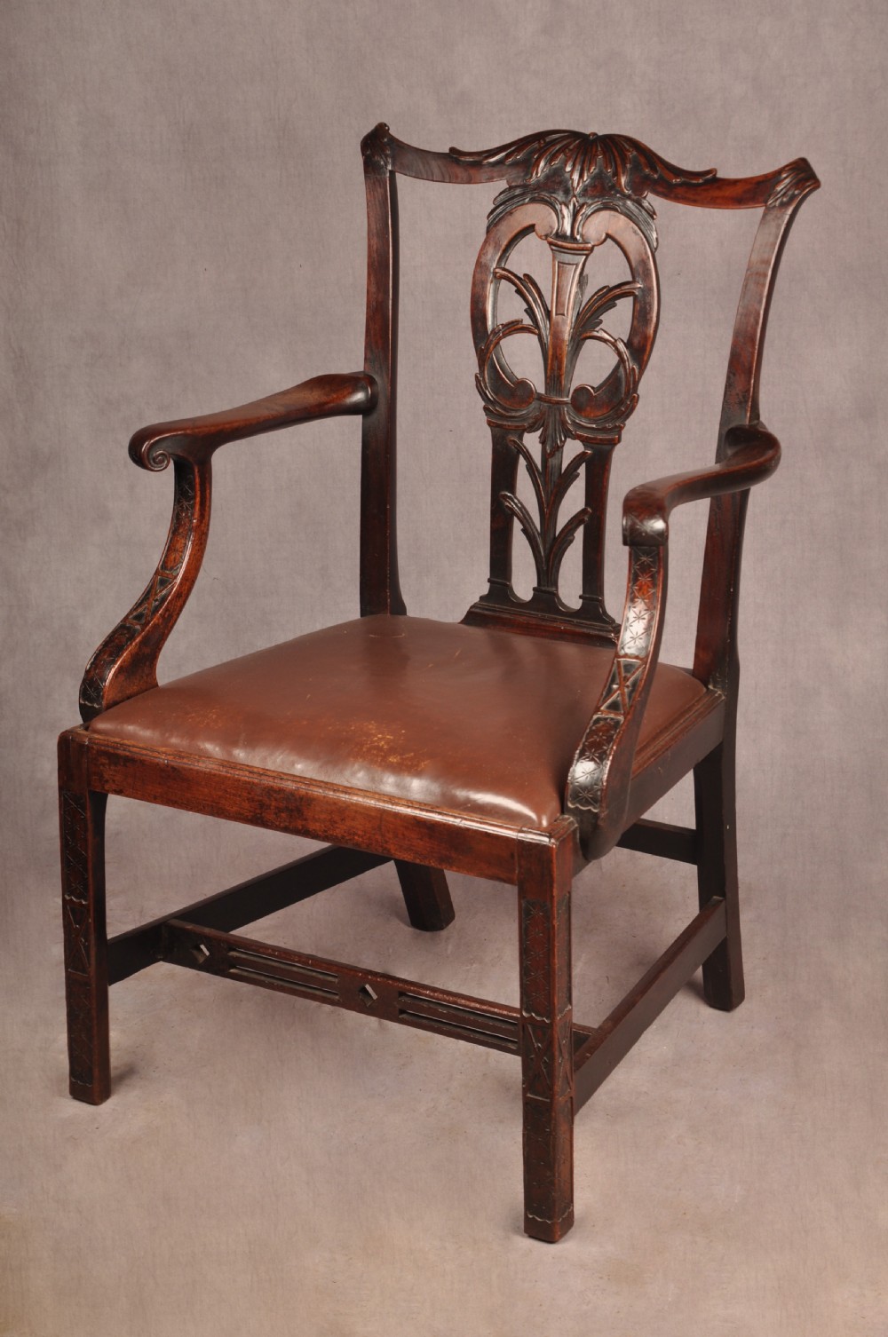 An 18th-century Chippendale carved mahogany armchair with a pierced splat, carved stretcher base, curved arms, and a warm brown leather seat. View VIII