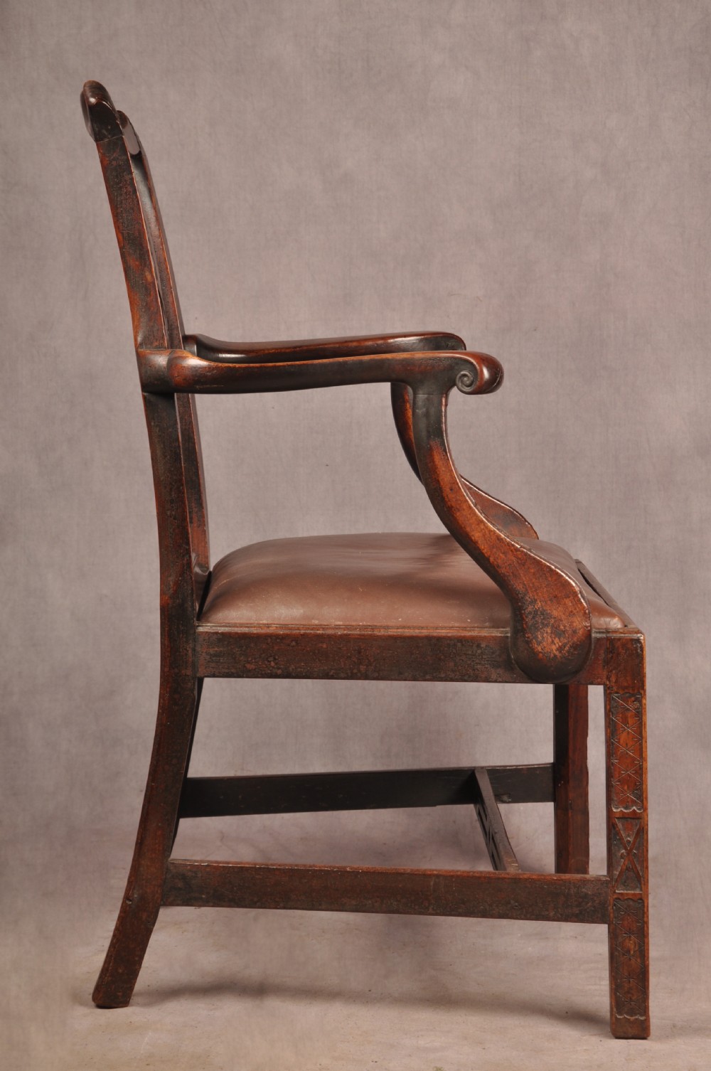 An 18th-century Chippendale carved mahogany armchair with a pierced splat, carved stretcher base, curved arms, and a warm brown leather seat. View IX