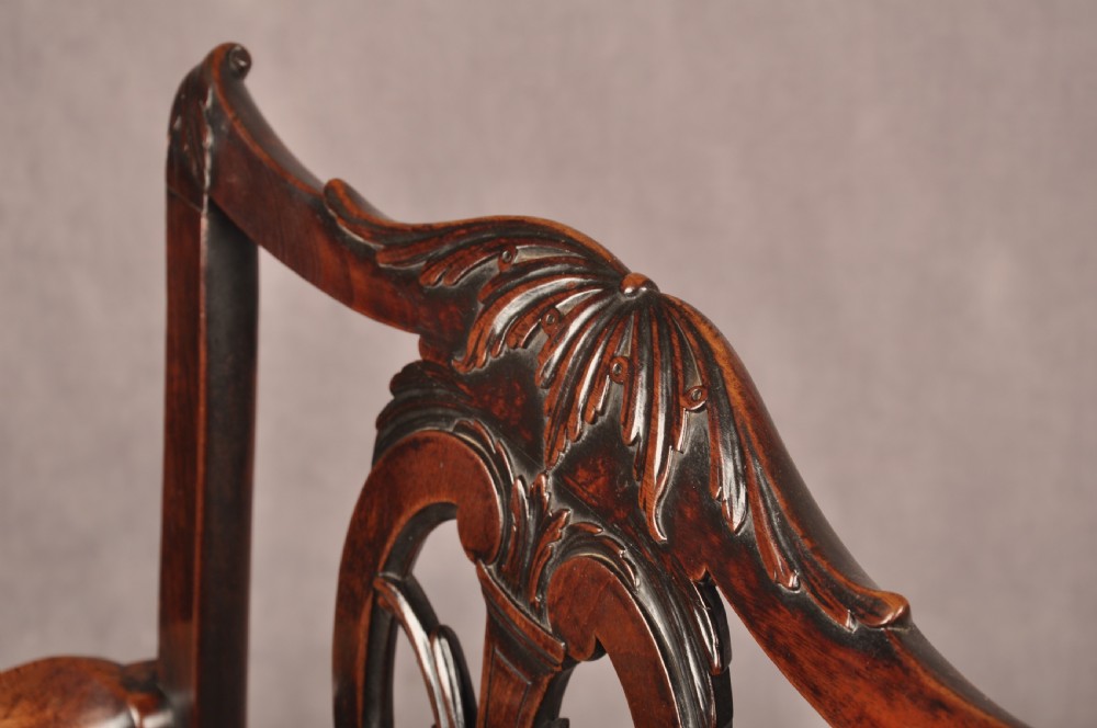 An 18th-century Chippendale carved mahogany armchair with a pierced splat, carved stretcher base, curved arms, and a warm brown leather seat. View X