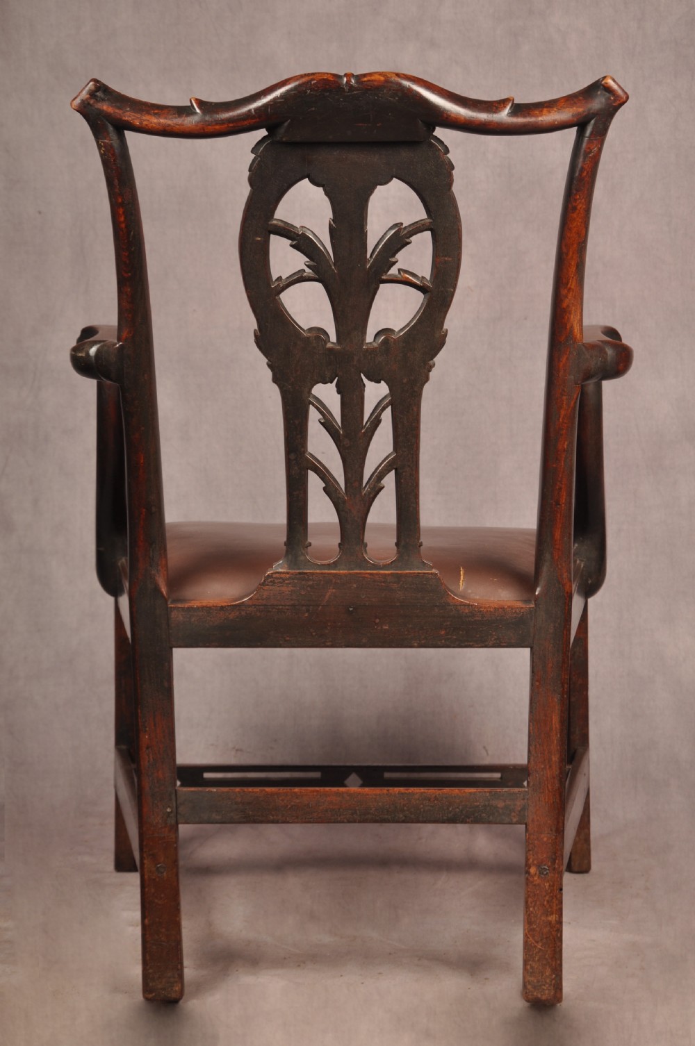 An 18th-century Chippendale carved mahogany armchair with a pierced splat, carved stretcher base, curved arms, and a warm brown leather seat. View XII