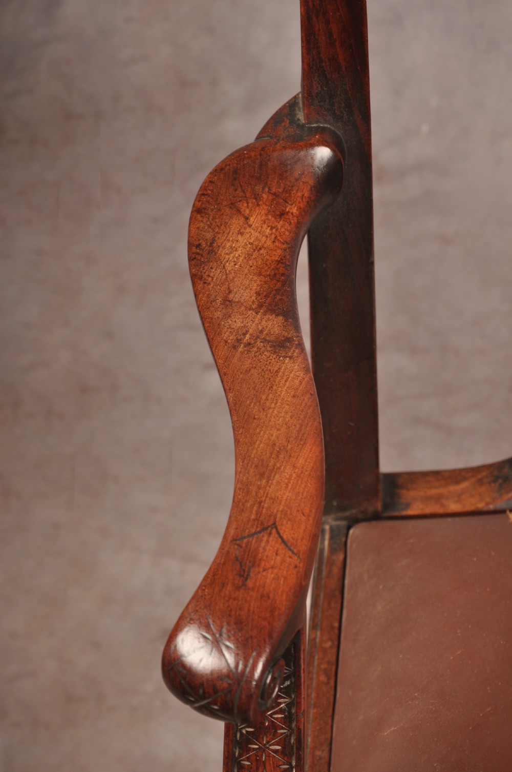 An 18th-century Chippendale carved mahogany armchair with a pierced splat, carved stretcher base, curved arms, and a warm brown leather seat. View XIII
