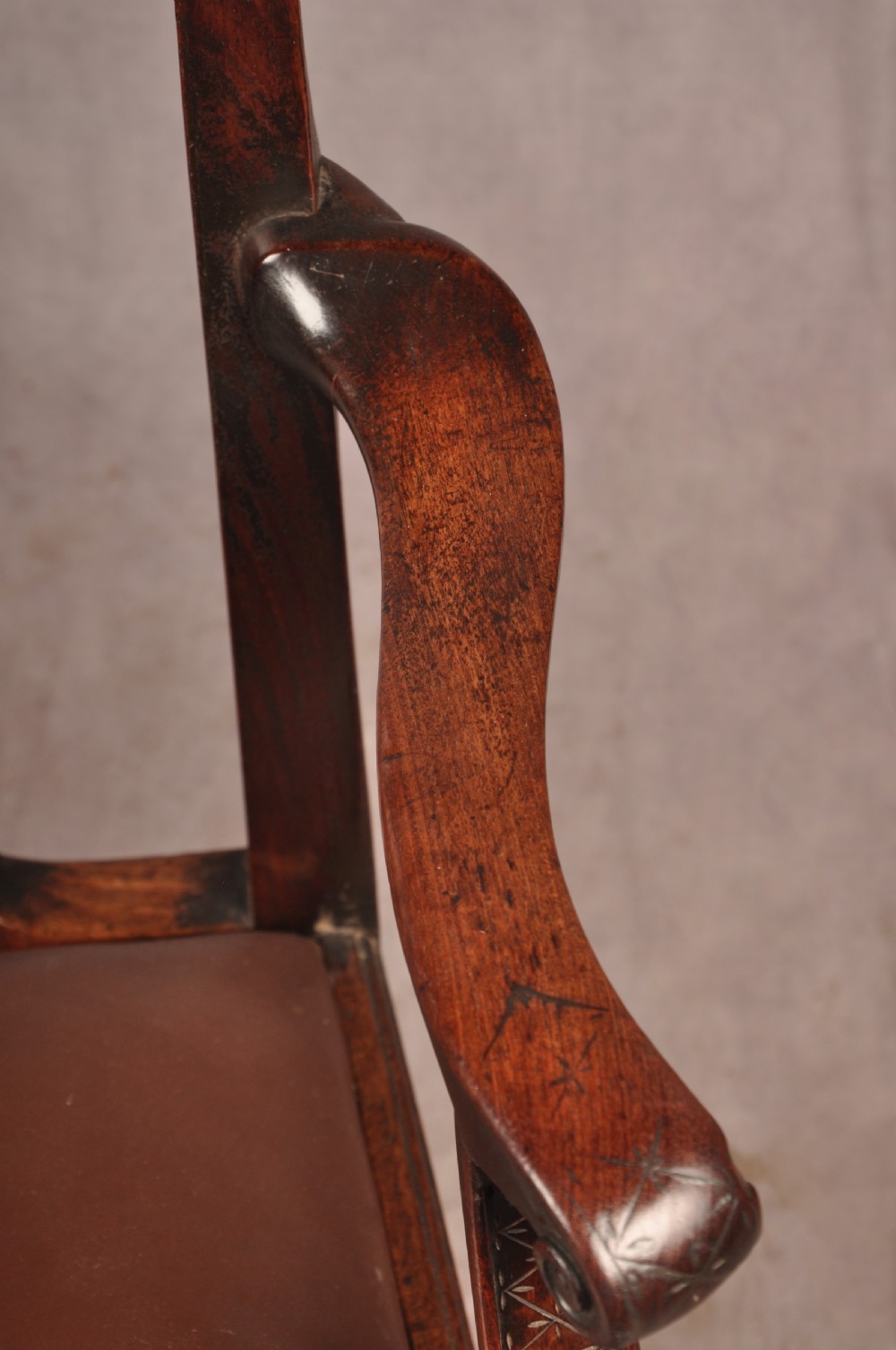 An 18th-century Chippendale carved mahogany armchair with a pierced splat, carved stretcher base, curved arms, and a warm brown leather seat. View XIV