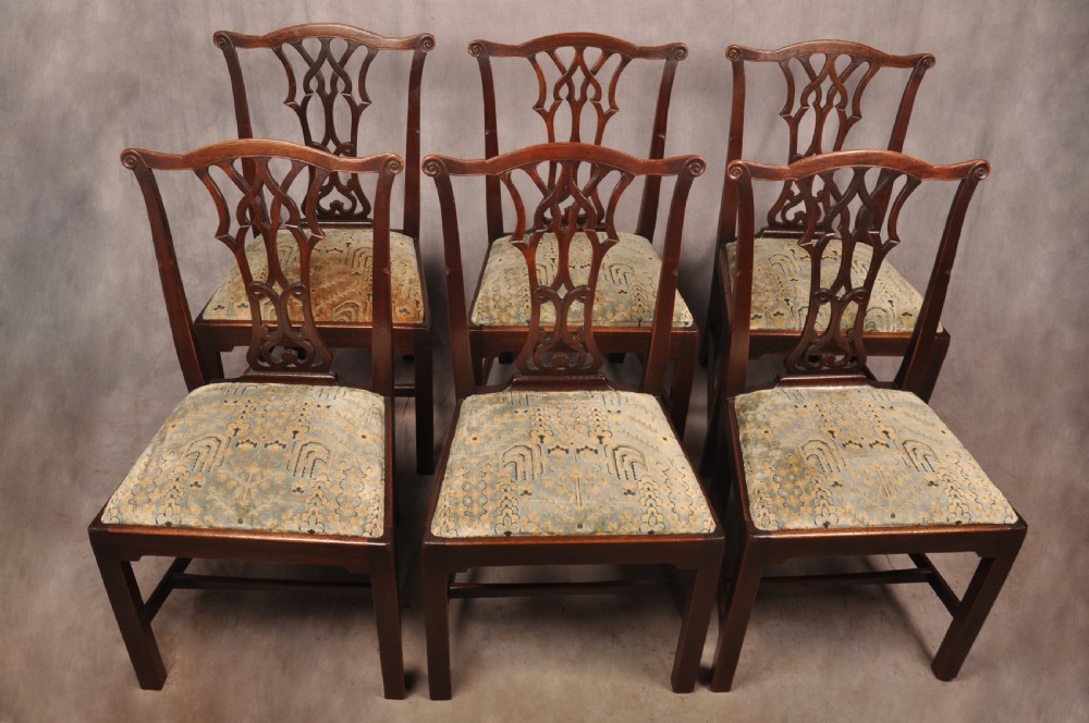 A set of six mahogany Chippendale style dining chairs featuring intricate pierced back splats and patterned upholstered drop-in seats.