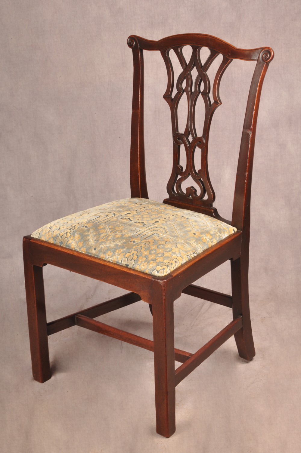 A set of six mahogany Chippendale style dining chairs featuring intricate pierced back splats and patterned upholstered drop-in seats. View V